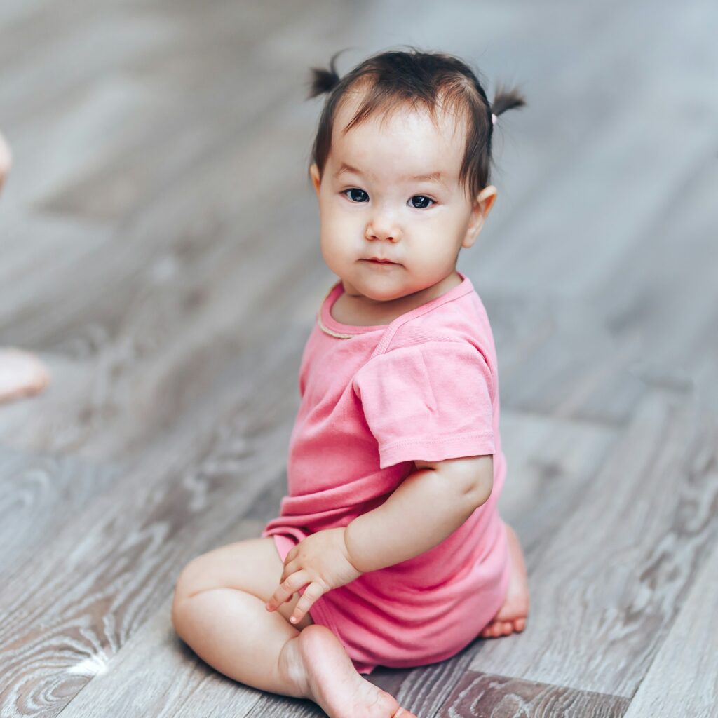 Beautiful cute baby kazakh one year old girl sittimg on floor at home