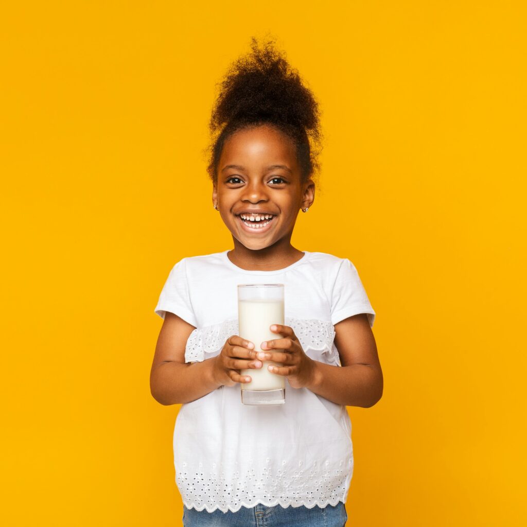 Cute afro girl enjoying glass of milk